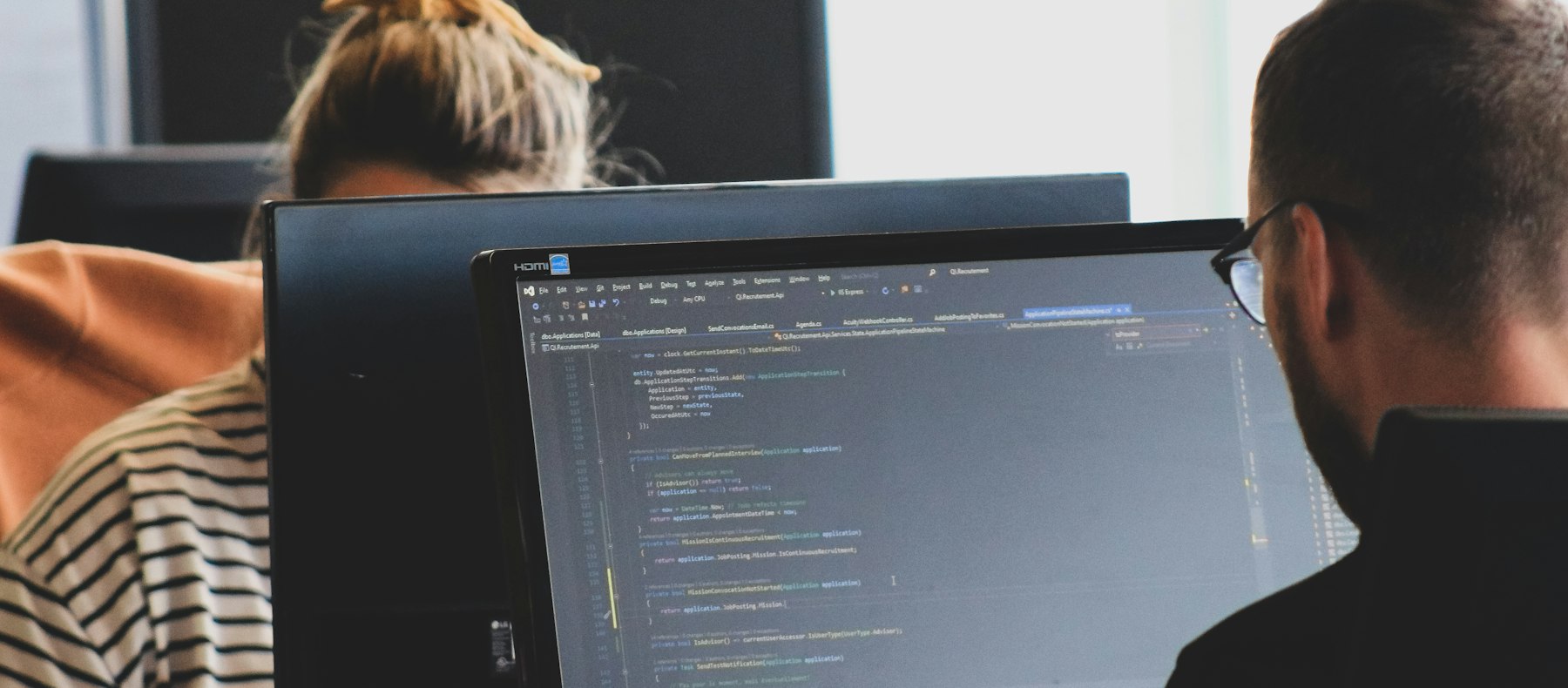 Entwicklerteam an Bildschirmen mit Programmcode